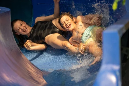 Kinder rutschen freudig auf einer blauen Wasserrutsche